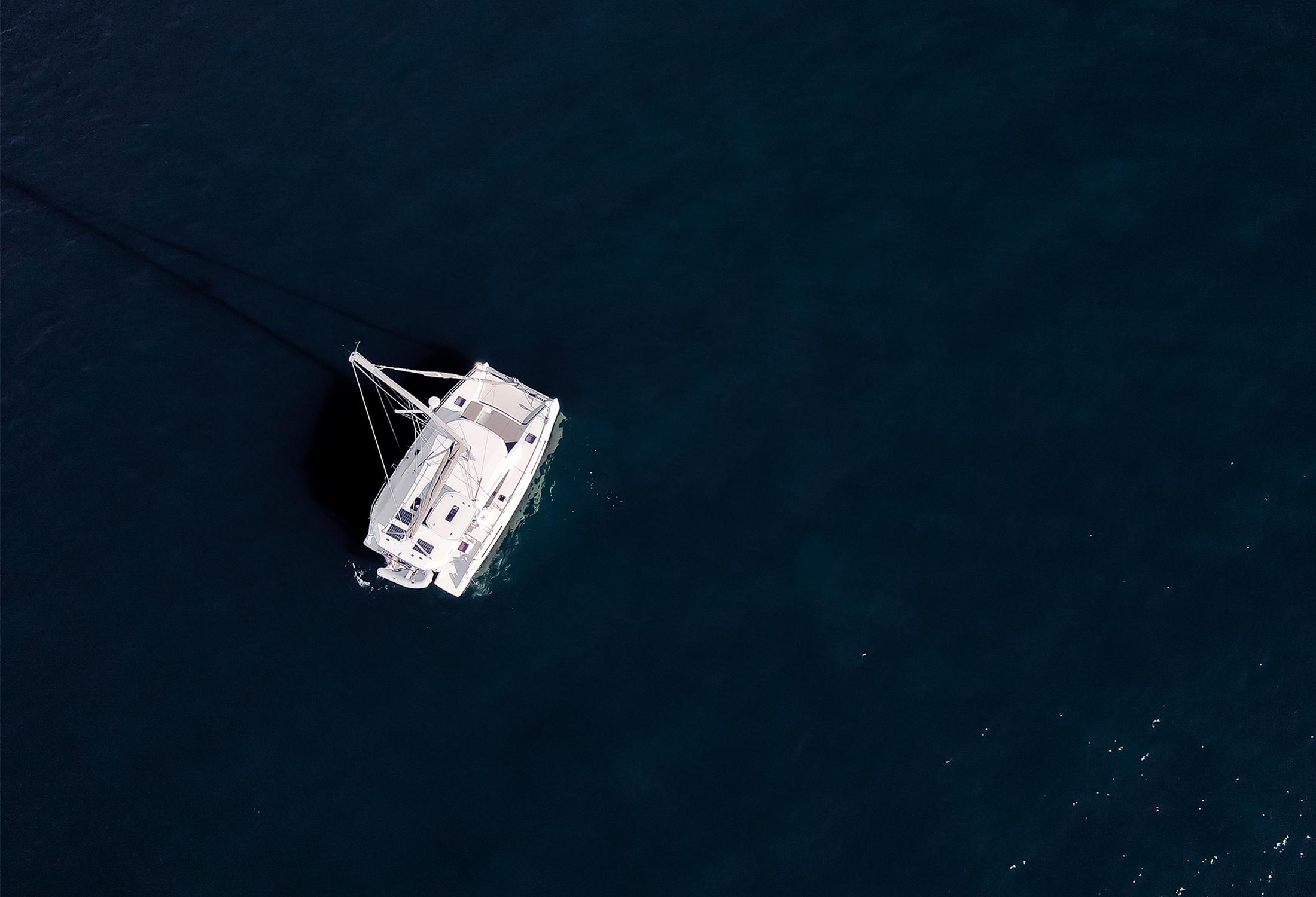 background image; a private catamaran under sail from above.