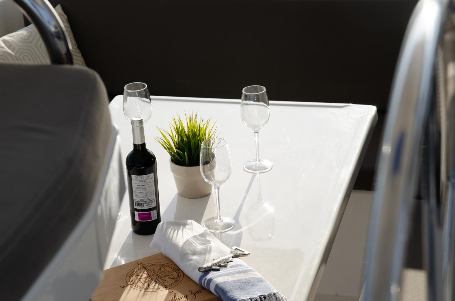 A bottle of wine and glasses on the aft table during a sailboat charter.